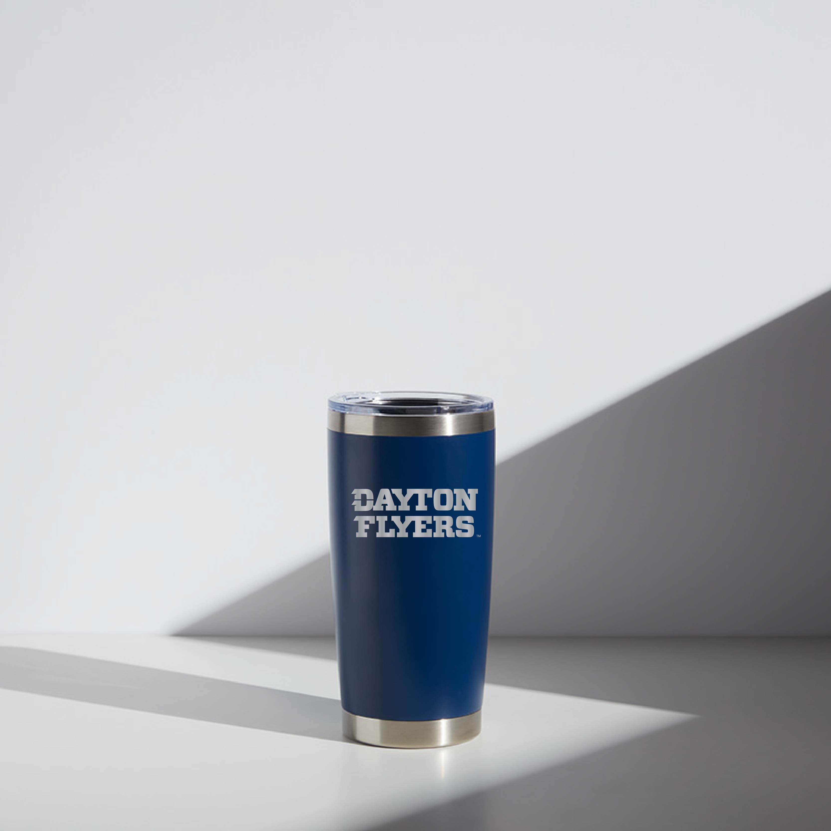 Alt text: "20 oz WATR tumbler in blue with 'Dayton Flyers' logo printed in white on the side, featuring a clear lid and silver rim, displayed against a light grey background with shadow play."