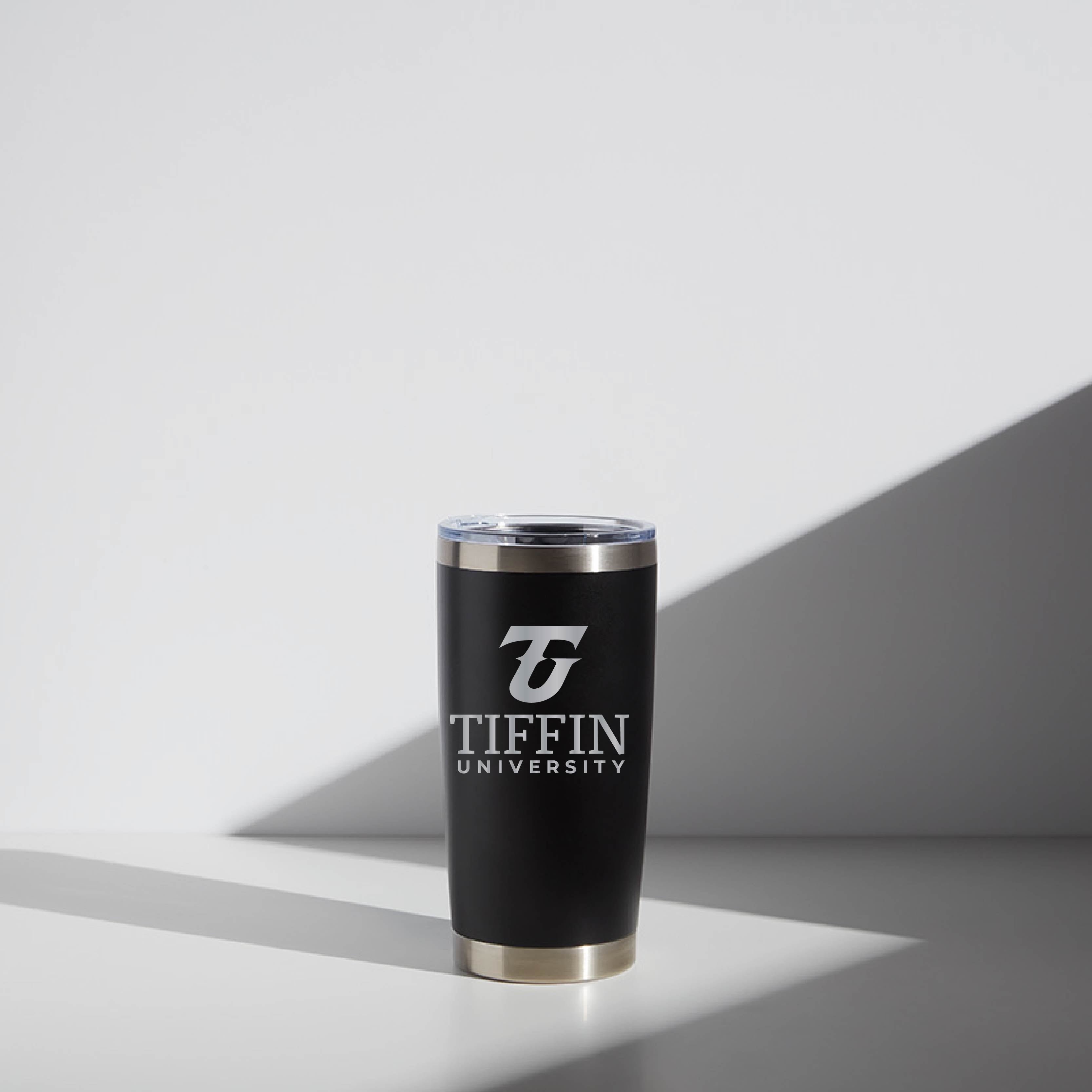 Black 20 oz WATR tumbler with Tiffin University logo, featuring a clear lid and a minimalistic design, displayed on a light background with soft shadows.