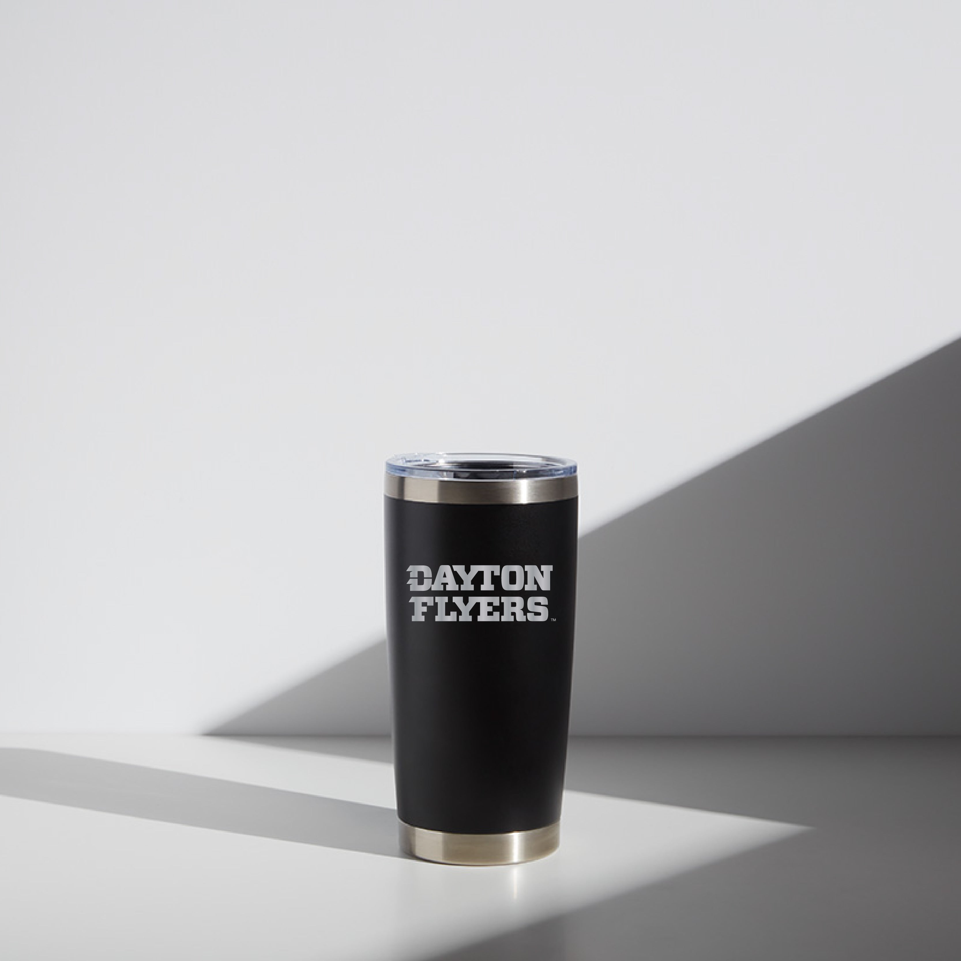 20 oz black WATR tumbler with 'Dayton Flyers' logo, clear lid, and silver rim, staged on a white surface with shadow accents.