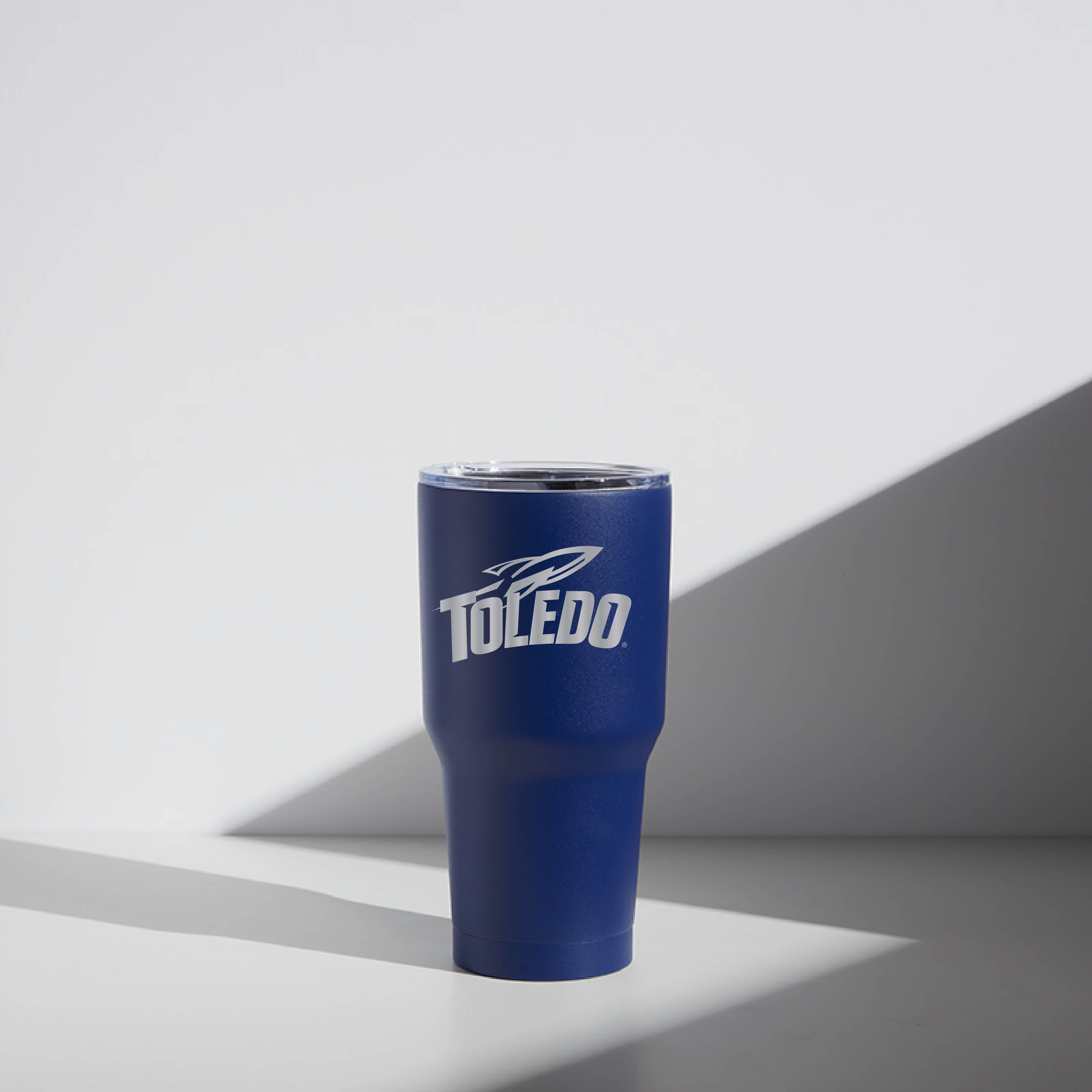 A blue 30 oz stainless steel tumbler with 'Toledo' text and logo printed on the side, featuring a magnetic lid.