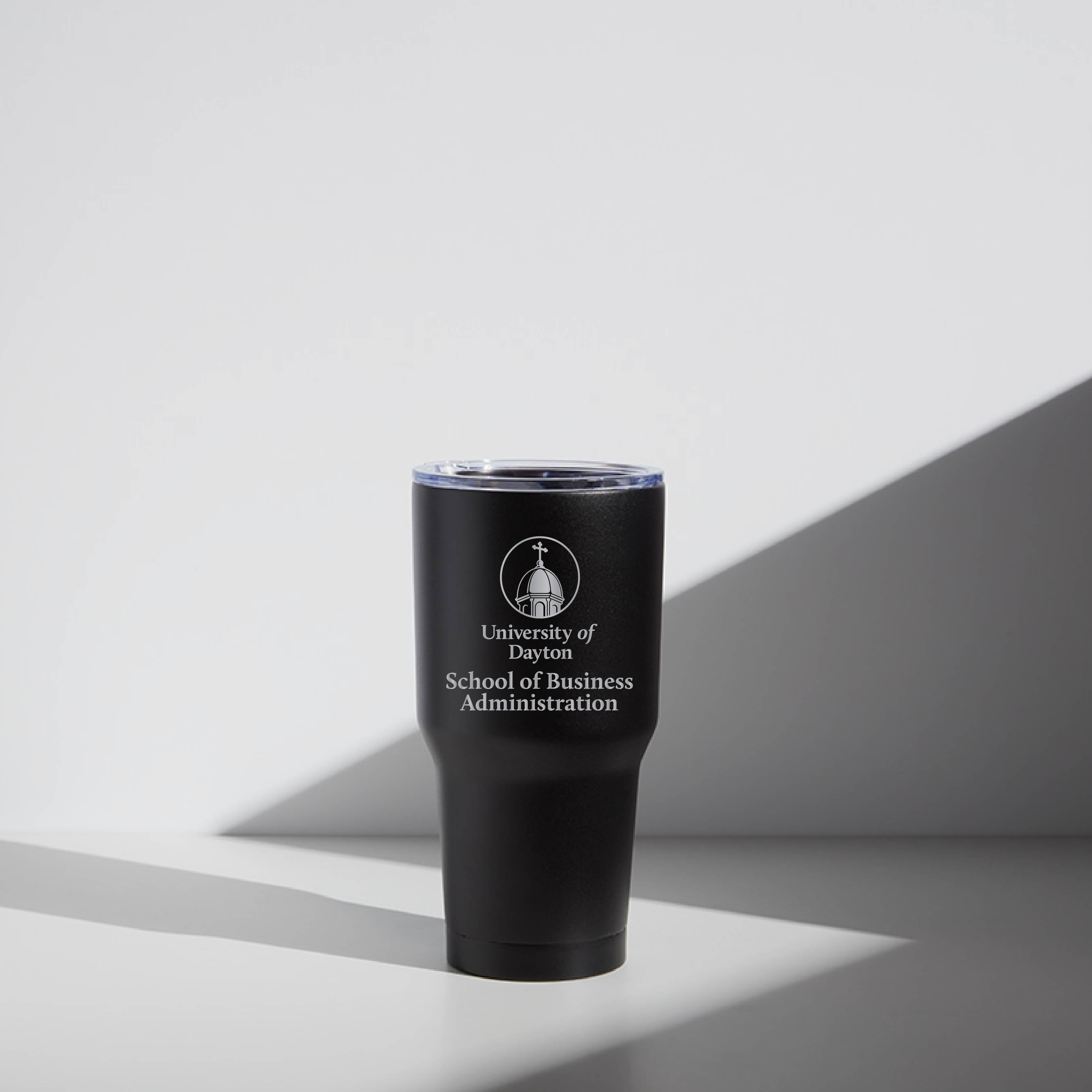 A black stainless steel tumbler with the University of Dayton School of Business Administration logo.